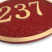A close-up view of a round house number plaque constructed from cast bronze