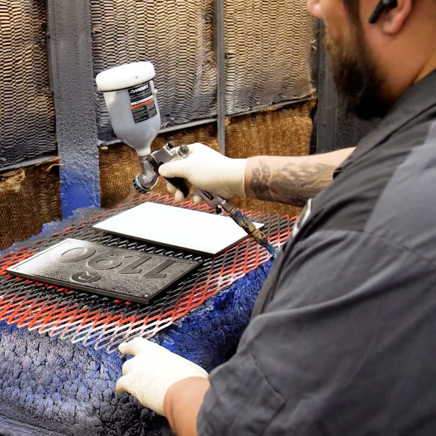 man spraying black paint on custom cast aluminum address plaque