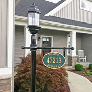 An example of an oval address sige post assembly with a post-top light, in front of a tan home