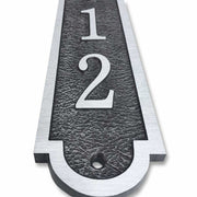 An up-close view of a 3x16 vertical house number plaque made from cast bronze